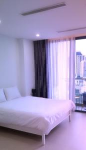 a bedroom with a white bed and a large window at Scenia Bay Residence Nha Trang in Nha Trang