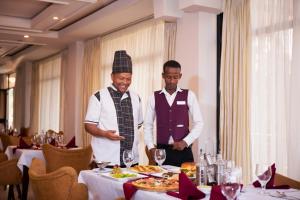 twee mannen staan voor een tafel met eten bij Filagot Hotel in Adama