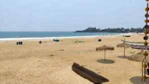 a beach with some straw umbrellas and the ocean at Royal cottage in Palolem
