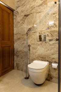 a bathroom with a toilet and a stone wall at The Ecstasy Hotel in Lucknow