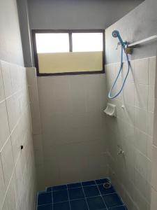 a bathroom with a shower with a window and a blue tile floor at Saran Hostel krabi Thailand in Krabi town