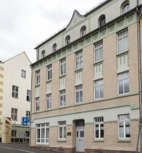 stary ceglany budynek z oknami wychodzącymi na ulicę w obiekcie Studiowohnungen Am Neuberinhaus F&G Apartments w mieście Reichenbach im Vogtland