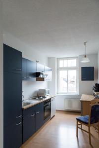 kuchnia z niebieskimi szafkami, stołem i oknem w obiekcie Studiowohnungen Am Neuberinhaus F&G Apartments w mieście Reichenbach im Vogtland