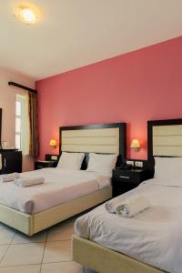 two beds in a hotel room with red walls at Hotel Kyani Akti in Xylokastro