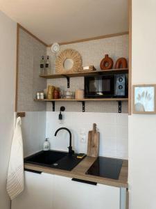 eine Küche mit einer Spüle und einer Mikrowelle in der Unterkunft Studio avec accès plage et mer in Dinard