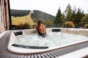 a woman is in a bath tub with water at Pytloun Wellness Hotel Harrachov in Harrachov