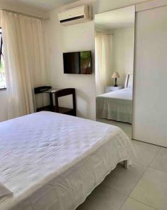 グアラジュバにあるSeu cantinho no paraíso de Guarajuba - Bahiaのベッドルーム1室(ベッド1台、デスク、テレビ付)