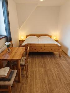 een slaapkamer met een bed en een houten tafel bij Penzion U Vody in Horní Bečva