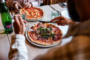 a group of people sitting at a table with two pizzas at Pytloun Wellness Hotel Harrachov in Harrachov