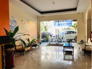 a living room with chairs and tables and a large window at Hotel Candra Kirana Syariah Prawirotaman Mitra RedDoorz in Yogyakarta