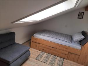 a bed and a couch in a room with a window at Fewo beim Schmied Straßkirchen in Vogtareuth