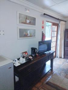 a living room with a television on a wooden table at Lapalosa Lodge in Centurion
