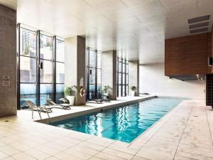 a large swimming pool with chairs in a building at Pride CBD Skyline View 2B2B Apartment LV32 in Melbourne