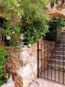 a gate in a stone wall with flowers and plants at Holiday house Sicily in Borgetto