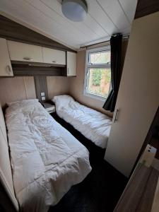 een kleine slaapkamer met 2 bedden en een raam bij Ruim Chalet, midden in het bos! in Nunspeet