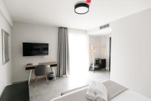 Comfort City Suites & Rooms في لاريسا: غرفة نوم بسرير ومكتب وتلفزيون
