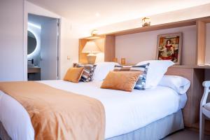 um quarto com uma grande cama branca com almofadas em Hotel Monells Summum em Monells