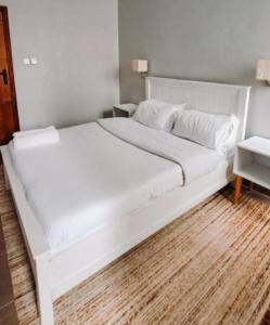 een groot wit bed in een slaapkamer met een houten vloer bij Chaka Homes in Kiganjo