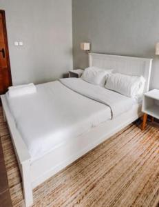 ein großes weißes Bett in einem Schlafzimmer mit Holzboden in der Unterkunft Chaka Homes in Kiganjo