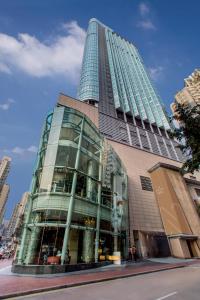 a tall building with glass windows on a city street at Nina Hotel Causeway Bay in Hong Kong