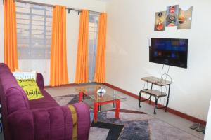 ein Wohnzimmer mit einem lila Sofa und einem TV in der Unterkunft Chaka Homes in Kiganjo