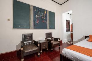 een slaapkamer met een bed, 2 stoelen en een schoolbord bij Oryza Hotel Malioboro in Sentool