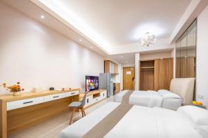 a hotel room with a bed and a desk and a tv at Chengdu Yayu Aparthotel in Chengdu