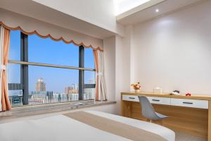 a bedroom with a desk and a large window at Chengdu Yayu Aparthotel in Chengdu