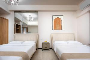 two beds in a room with white walls at Chengdu Yayu Aparthotel in Chengdu