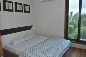 a bedroom with a bed with a large window at Casa De Diu in Diu
