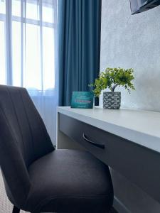 a chair sitting in front of a desk with a plant at De Marco Hotel in Kostanay