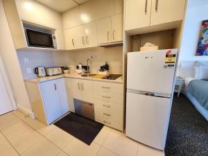 a small kitchen with a white refrigerator and a couch at Deluxe Private Apartment and Studio - Ocean Views in Gold Coast