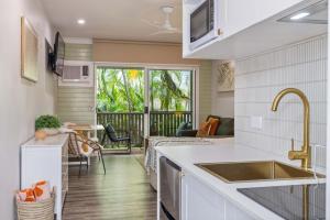 a kitchen with a sink and a living room at Tropic Retreat in Port Douglas