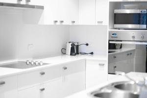 a white kitchen with a sink and a microwave at Beachfront 2 in Mollymook