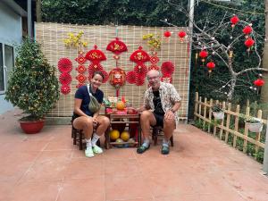 a man and woman sitting at a table in a garden at Hà Trang Homestay in Nghĩa Lộ