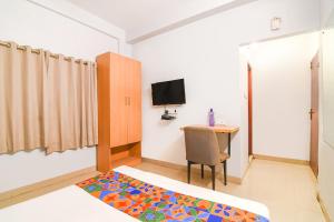 a room with a bed and a desk and a television at FabExpress P3 in Ballygunge