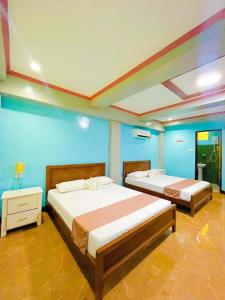 two beds in a room with blue walls at Keyun's Inn- Across Cloud 9 in General Luna