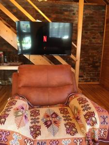 ein Wohnzimmer mit einem Stuhl und einem TV in der Unterkunft "River paradise" Vikendica sa bazenom, ladarom i kaminom na samoj obali Vrbasa Banja Luka in Banja Luka