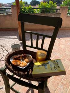 une assiette de beignets et un livre sur une chaise dans l'établissement Sirem Boutique Apartament, à Assemini