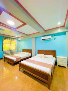 two beds in a room with blue walls at Keyun's Inn- Across Cloud 9 in General Luna