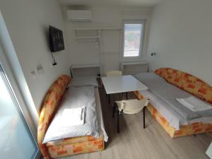 a small room with two beds and a table at BÖJTÖS apartmány NESVADY in Nesvady