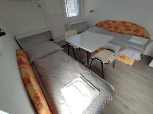 a room with two beds and a table and chairs at BÖJTÖS apartmány NESVADY in Nesvady