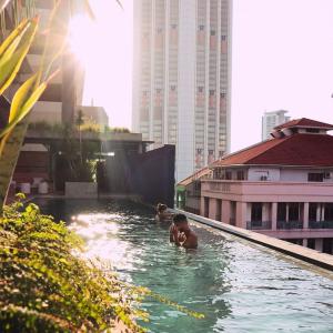 zwei Personen schwimmen in einem Pool auf einem Gebäude in der Unterkunft Else Kuala Lumpur in Kuala Lumpur