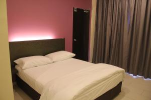 a bedroom with a white bed with a pink wall at Hotel Mirage PD in Port Dickson