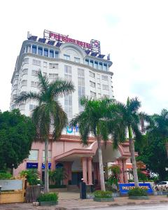 un grand bâtiment avec des palmiers devant lui dans l'établissement Phù Đổng Hotel Thanh Hóa, à Thanh Hóa