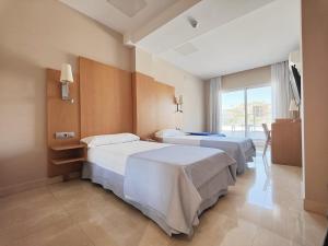 a hotel room with two beds and a window at Hotel La Cala Finestrat in Cala de Finestrat