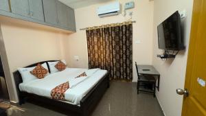 a hotel room with a bed and a television at Alexa Service Appartments (1BHK,2BHK with Kitchen) in Tirupati