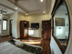 een kamer met een bed, een tv en een spiegel bij Hotel Sethi Legacy in Haridwār