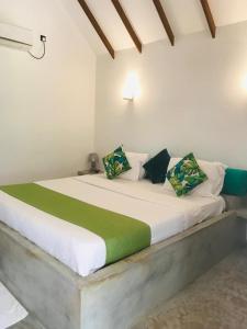 Una cama blanca con almohadas verdes y blancas. en The Tottam Beach Hotel - Trincomalee, en Trincomalee