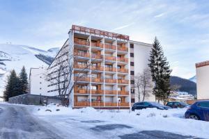 a building in the snow with cars parked in a parking lot at Cabourg - 20 - Appart belle expo - 6 pers in Les Deux Alpes +2 photos